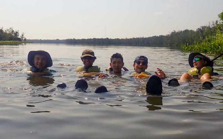 a group of teens swim while on a kayaking trip with outward bound